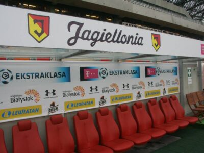 Obramowanie ławki rezerwowych reklamą Jagiellonii Białystok